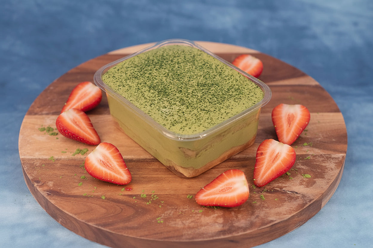 Keto matcha pandan box cake dessert on a wooden platter with matcha powder.