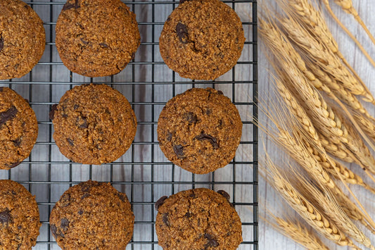 Keto chocolate chip cookies on a baking rack with wheat stalks on a wooden table