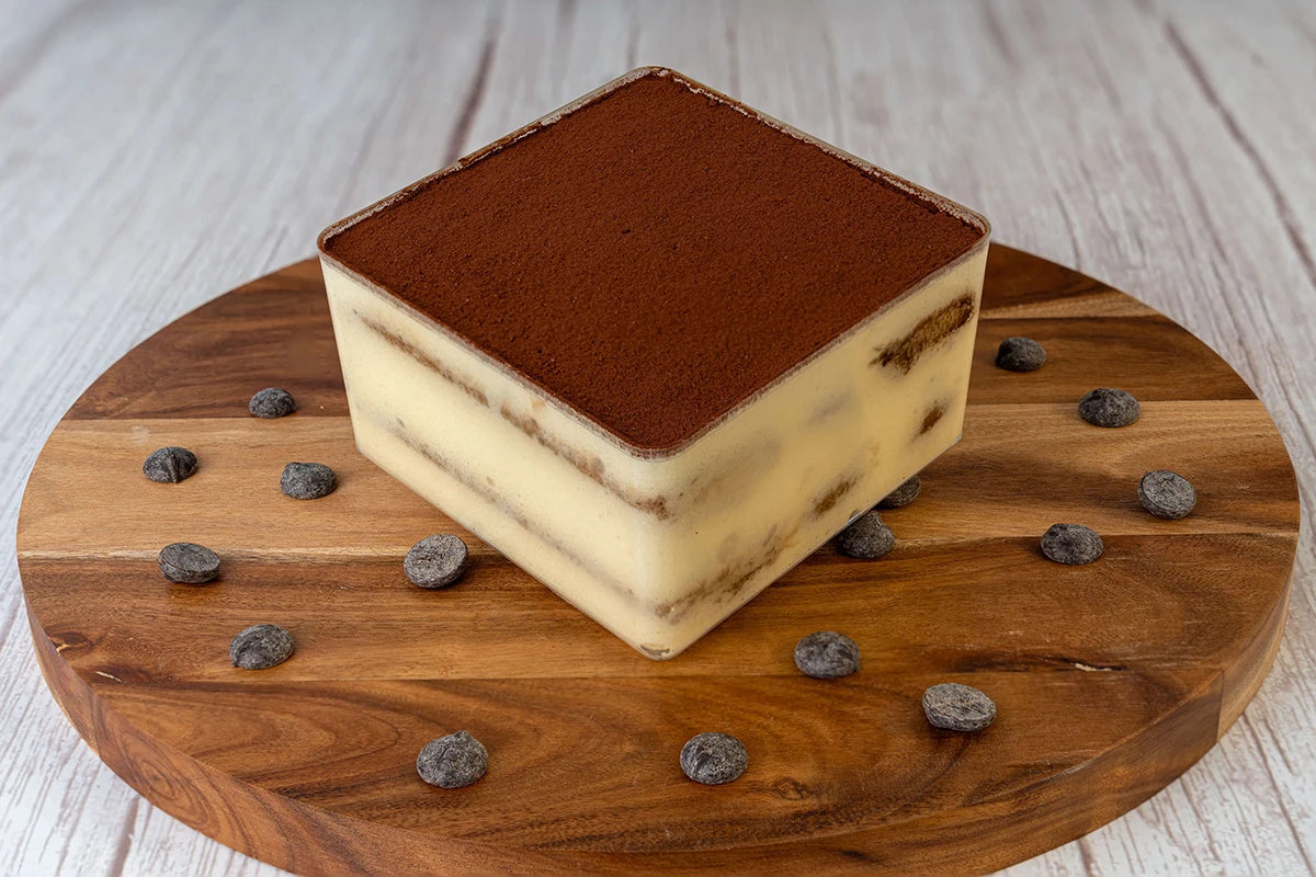 Tiramisu box cake dessert on a wooden table with chocolate shavings