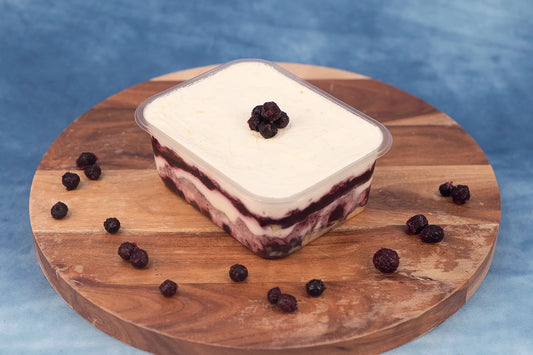 Keto blueberry lemon box cake dessert on a wooden platter with organic blueberries.