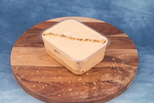 Keto thai milk tea box cake dessert on a wooden platter with coconut shavings.