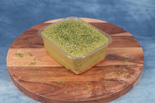 Keto matcha pandan box cake dessert on a wooden platter with matcha powder.