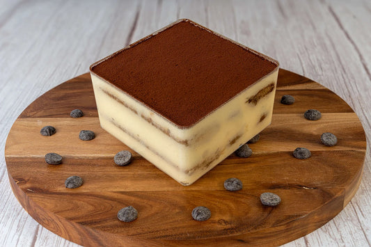 Tiramisu box cake dessert on a wooden table with chocolate shavings